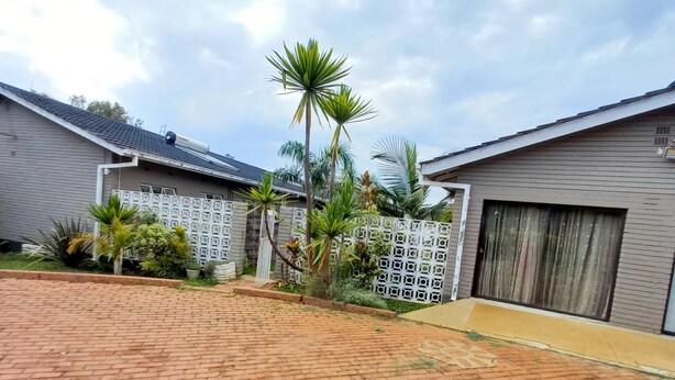 A courtyard with a brick floor, palm trees, and a white lattice fence. - Las Palmas Guest House (Harare)
