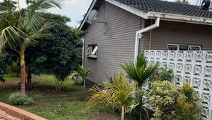 A residential house with a satellite dish, a white fence, and various plants. - Las Palmas Guest House (Harare)