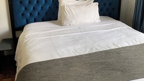 A neatly made bed with a tufted headboard, white bedding, and a grey throw. - Las Palmas Guest House (Harare)