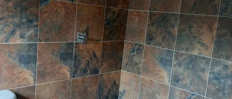 A bathroom with a toilet, a sink, and a shower area with tiled walls and floor.