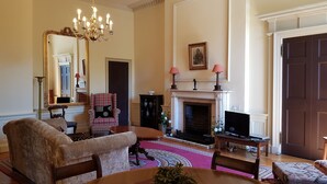A traditional living room with a fireplace, a large mirror, and classic furniture. - Classy Historic Edinburgh Apartment (Edinburgh)