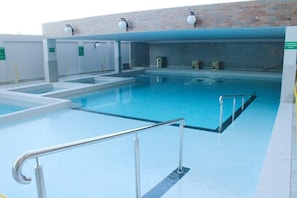 A swimming pool with multiple lanes, a changing room area, and a brick wall in the background. - Piazza Di Roma - Reserve Caldas (Caldas Novas)