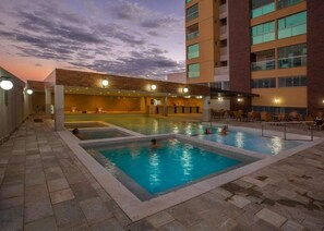 A rooftop swimming pool with multiple lanes, surrounded by lounge chairs and a building with a brick facade. - Piazza Di Roma - Reserve Caldas (Caldas Novas)