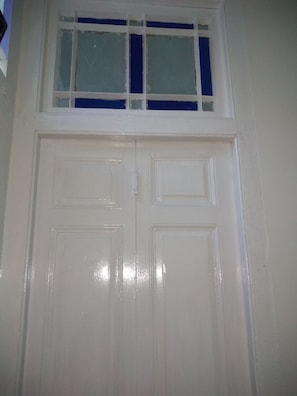 Une porte double blanche avec une fenêtre au-dessus.
