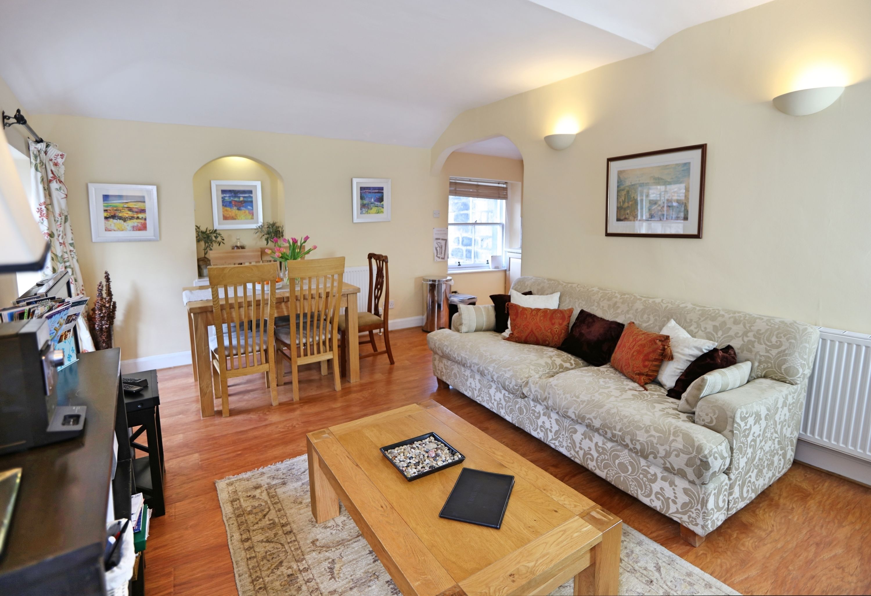 A living room with a sofa, coffee table, and dining area with chairs and a table.