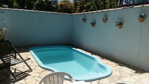 A small outdoor swimming pool with a stone floor, surrounded by a low wall. - Pousada Licuri (Santana do Riacho)