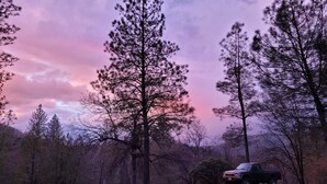 A truck parked in a grassy area with trees and a mountainous background. - Kozy Korner will be your home away from home to refresh and rest when traveling. (Midpines)