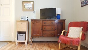 A room with a wooden cabinet, a television, a lamp, a red chair, and a framed picture on the wall. - Fantastic Edinburgh Apartment (Edinburgh)