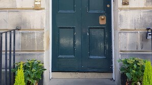A dark green door with a brass knocker, flanked by potted plants, and a number '31' sign above. - Quality Stay 3-Bedroom Apartment (Edinburgh)