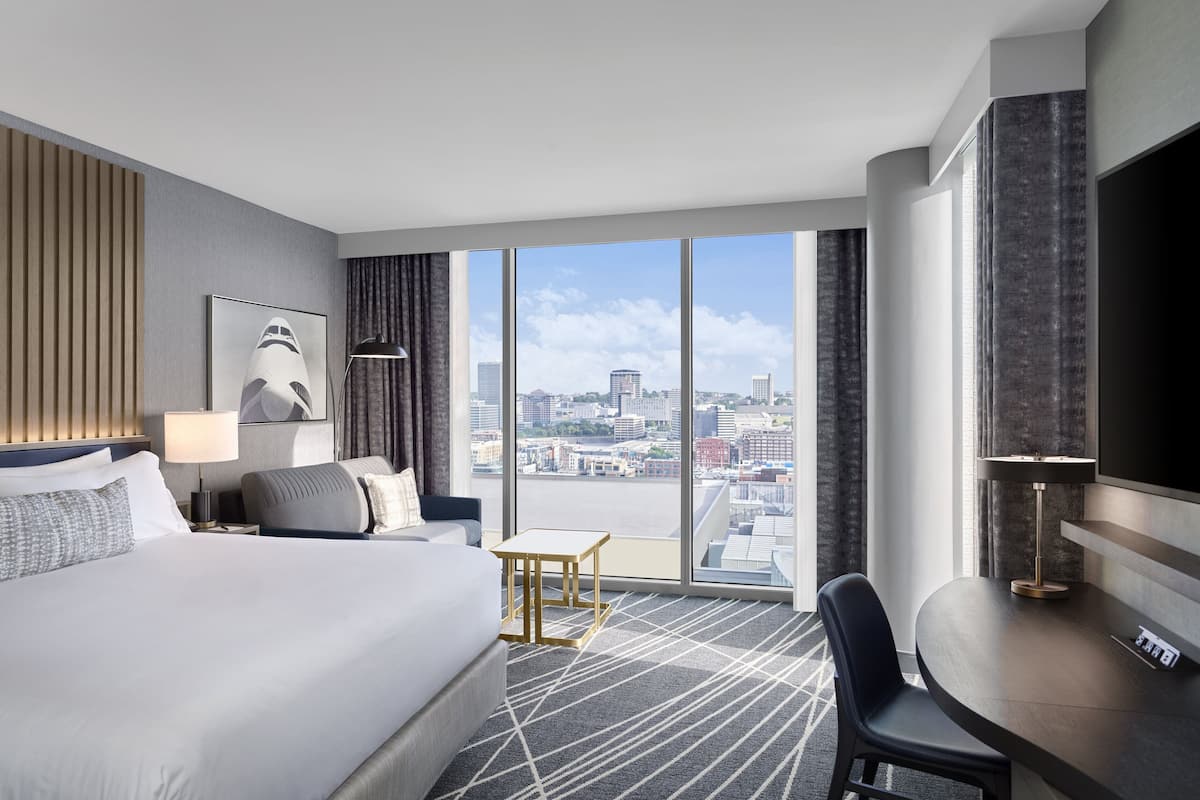 Habitación de hotel moderna con una cama grande, un escritorio y vistas a la ciudad.