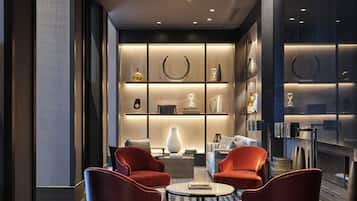 Un salón moderno con chimenea, sillones rojos y una estantería.