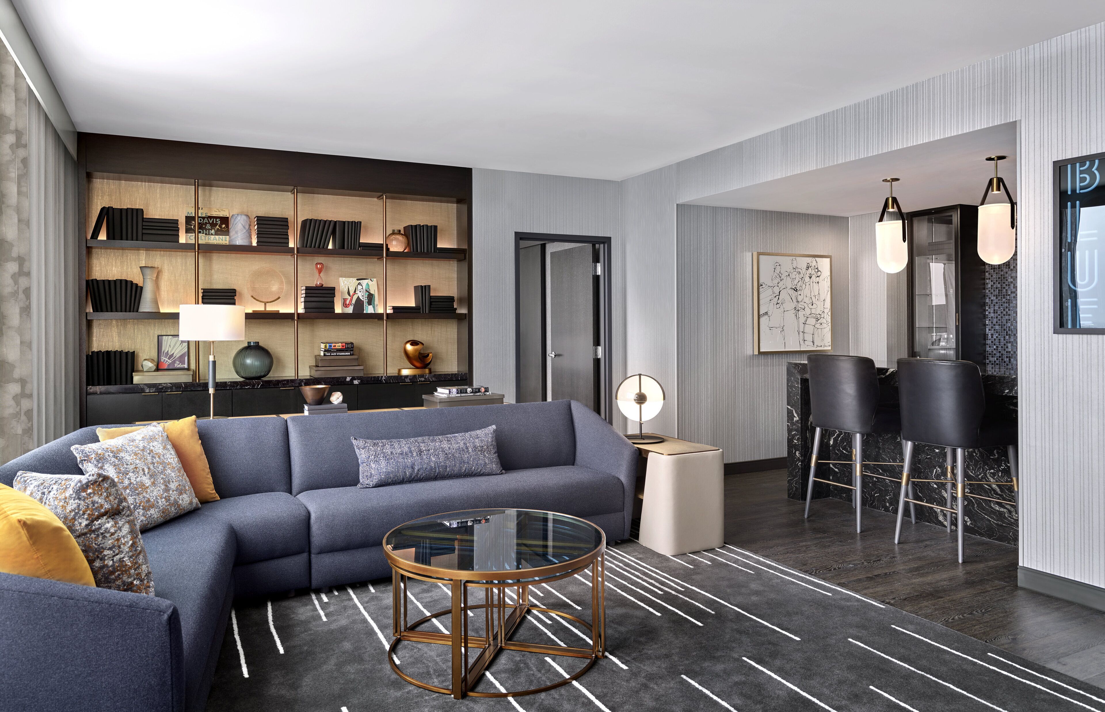 A modern living room with a sectional sofa, a glass coffee table, and a built-in bookshelf.
