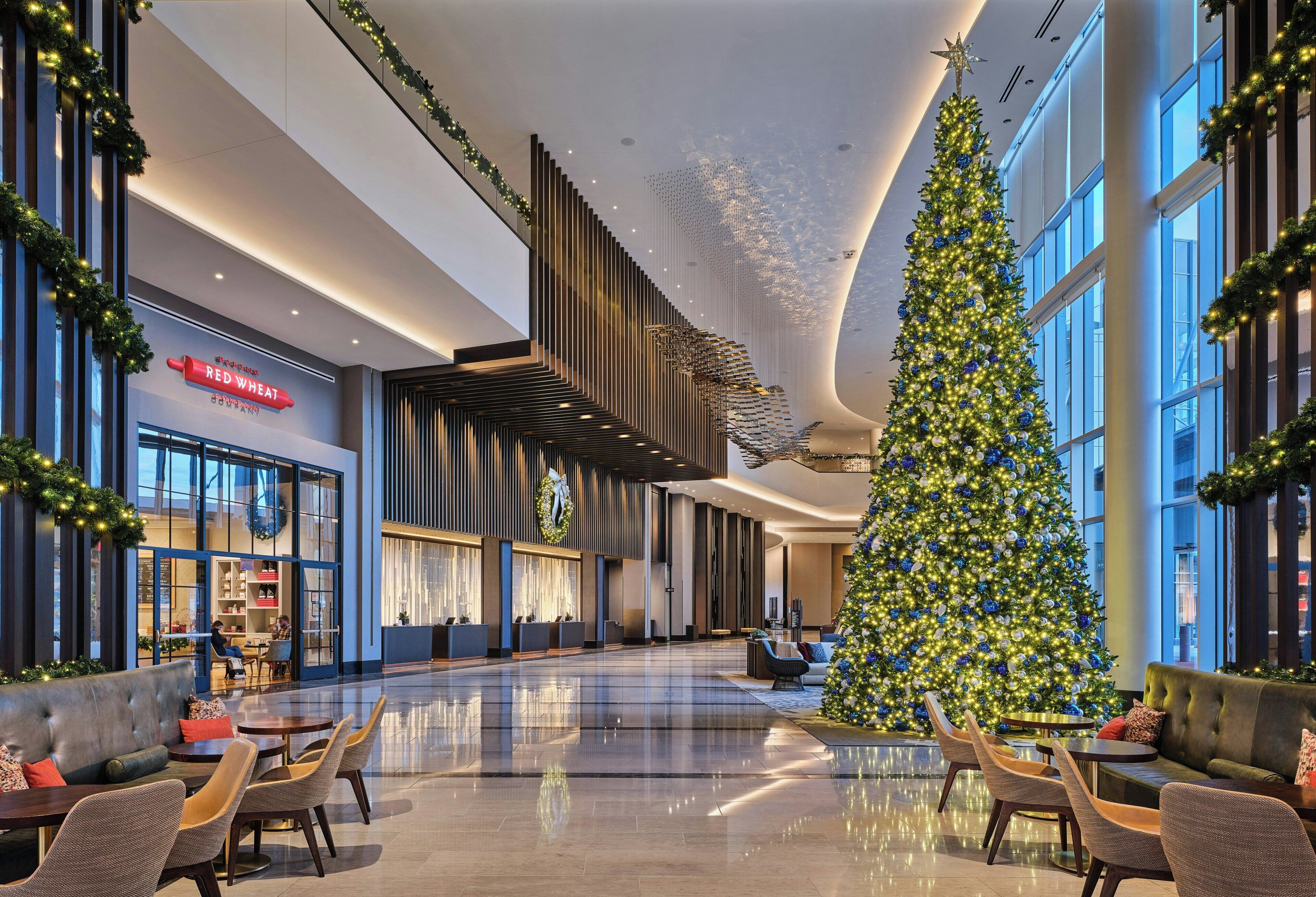 A spacious lobby with a large Christmas tree, seating areas, and a Red Wheat store.