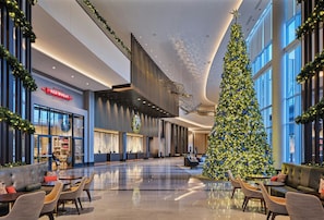 Un vestíbulo espacioso con un gran árbol de Navidad, zonas de estar y una tienda Red Wheat.