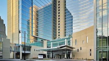Un hôtel moderne doté d’une façade en verre, d’une entrée couverte et d’une enseigne indiquant « LOEWS ».