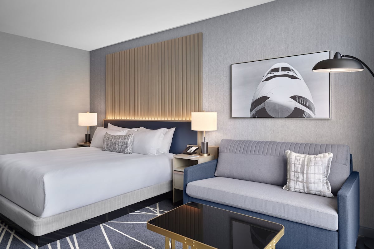 Una habitación de hotel con dos camas, un sofá, un escritorio y una mesita de centro.