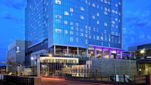 Un hotel moderno de gran altura con fachada de vidrio, donde se puede ver el nombre "LOEWS" en la parte superior.