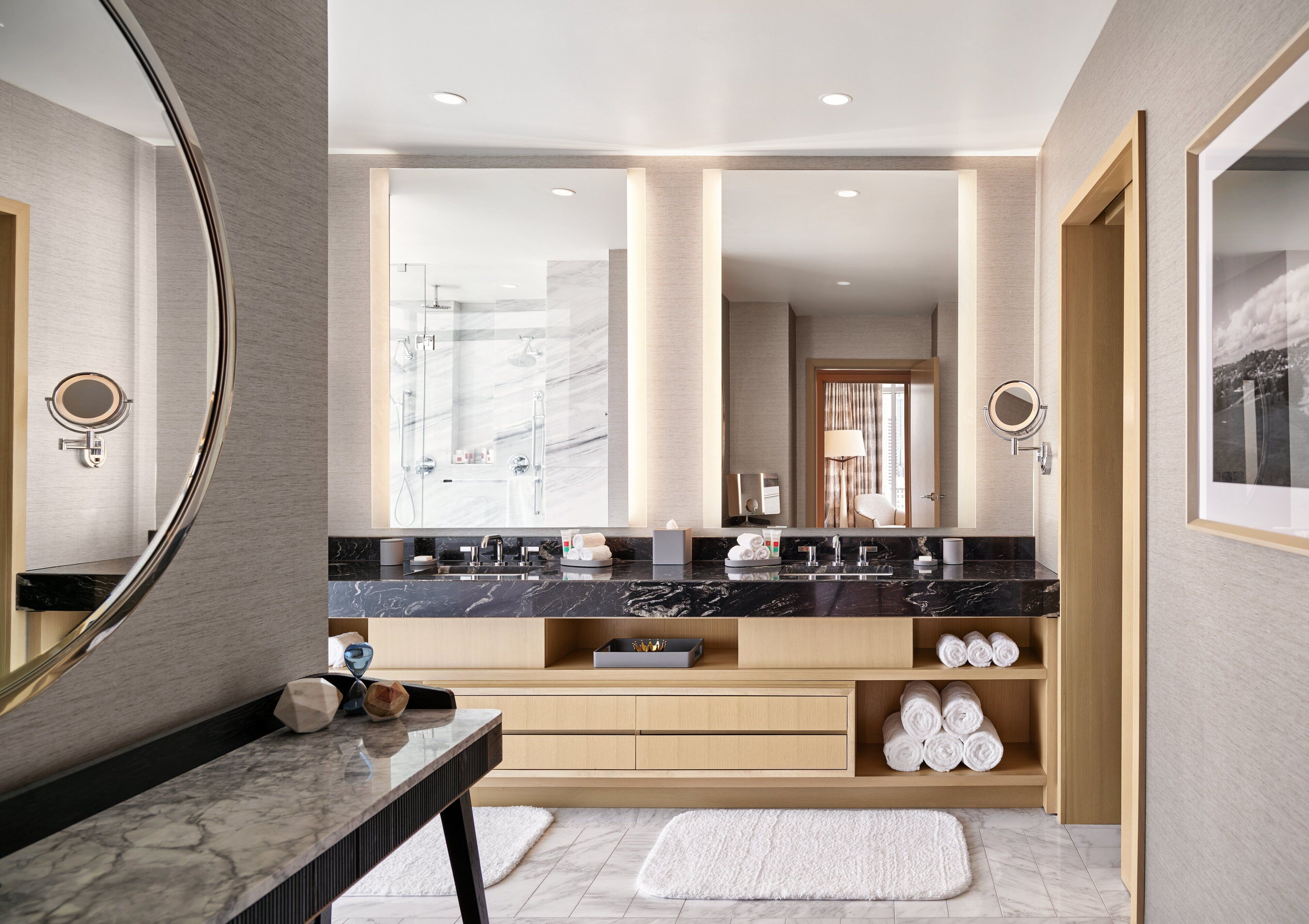 Un baño moderno con un espejo grande, dos lavabos, una ducha y un mueble de tocador con espacio de almacenamiento.