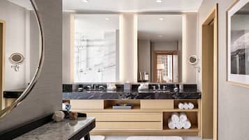 Un baño moderno con un espejo grande, dos lavabos, una ducha y un mueble de tocador con espacio de almacenamiento.