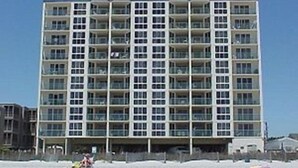 Un hotel de varios pisos con fachada uniforme, que cuenta con balcones en cada planta.