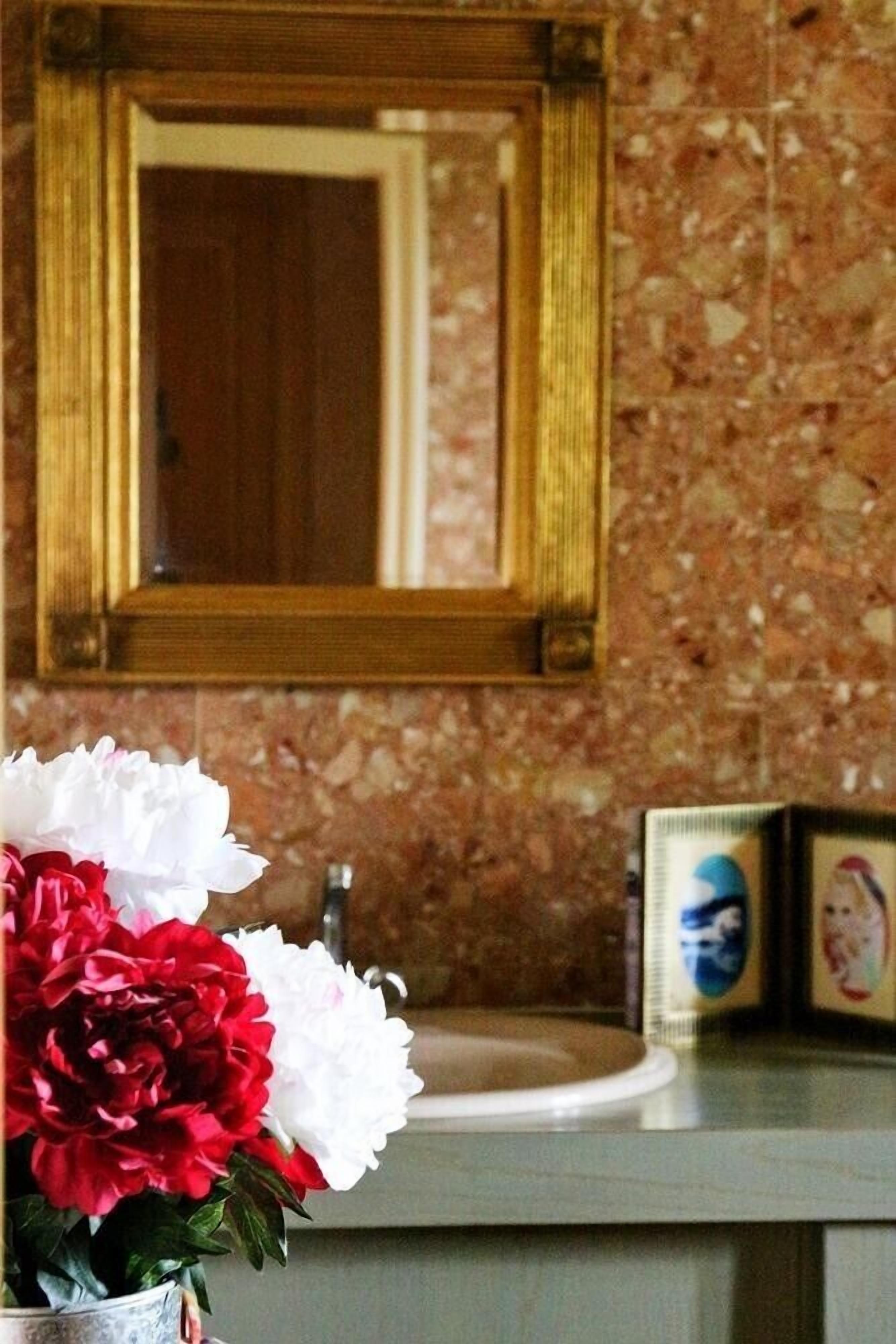 Un baño con salpicadero de mármol, un lavabo y un espejo.