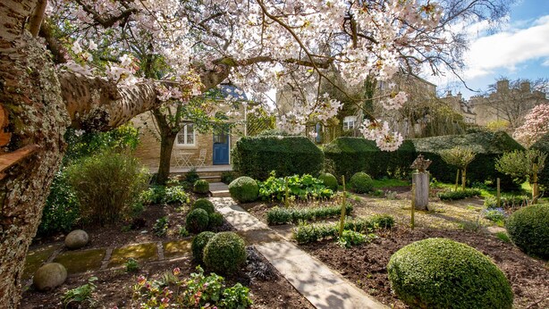 A garden with a pathway leading to a building with a blue door. - Converted Luxury Barn - The Potting Shed - Grade II listed (Cirencester)