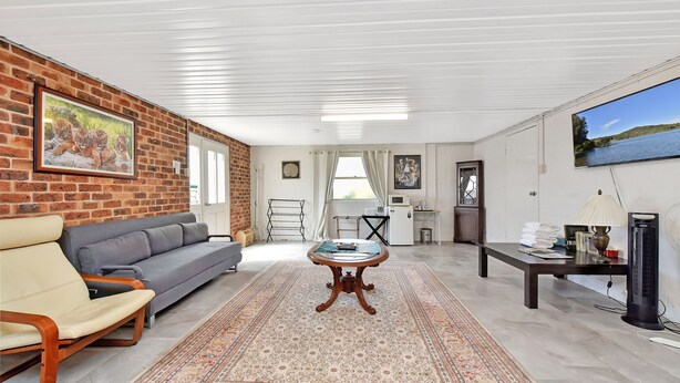 Un salon avec un canapé, une table basse, un tapis, un téléviseur et un mur en briques.