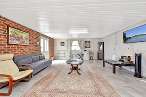 A living room with a sofa, a coffee table, a rug, a TV, and a brick wall.