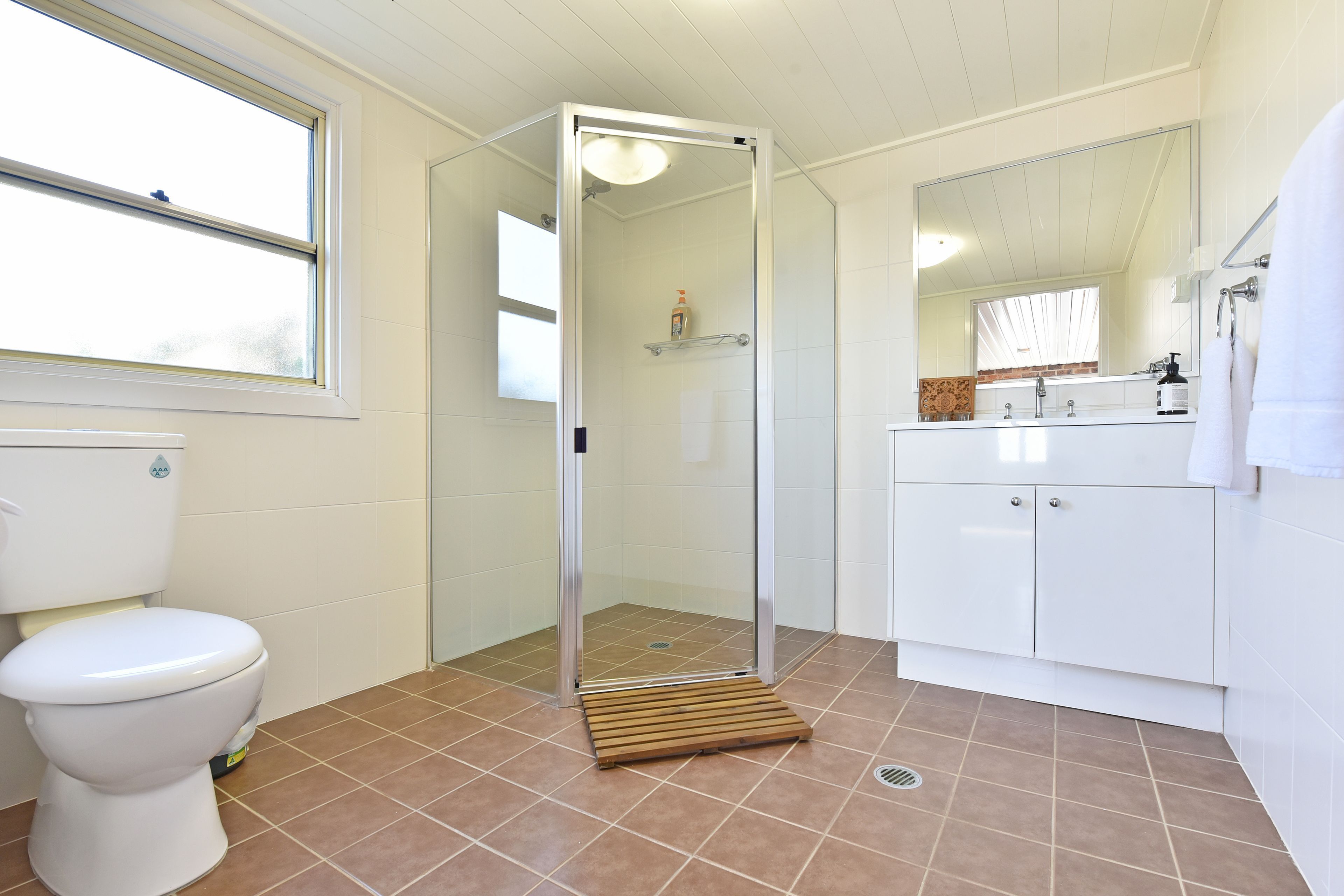 A bathroom with a toilet, a shower with a glass door, and a sink with a mirror.