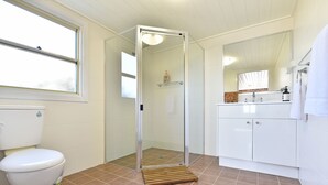 Une salle de bain comprenant des toilettes, une douche avec une porte en verre et un lavabo avec un miroir.
