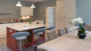 A modern kitchen with a central island, bar stools, and a dining table with chairs. - Authentic Central 3-Bedroom Apartment (Edinburgh)