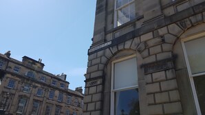 A historic building with a stone facade, a large arched window, and a sign reading "DRUMMOND PLACE". - Authentic Central 3-Bedroom Apartment (Edinburgh)
