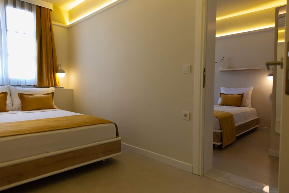 Una habitación de hotel con una cama grande, una mesita de noche con lámpara y una ventana con cortinas.