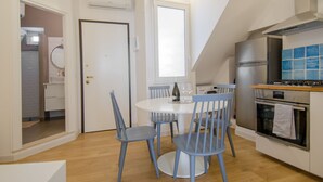 Una cocina moderna con comedor, que incluye una mesa redonda, sillas azules, horno empotrado y una ventana sobre el fregadero.