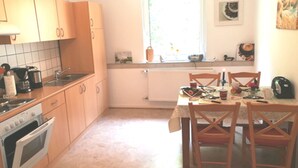 Une cuisine avec des meubles de rangement en bois, une cuisinière et une table à manger avec des chaises.