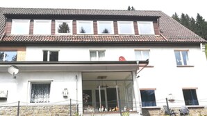 Une maison à deux étages, avec un toit recouvert de tuiles, un balcon doté d’une balustrade et une antenne parabolique.