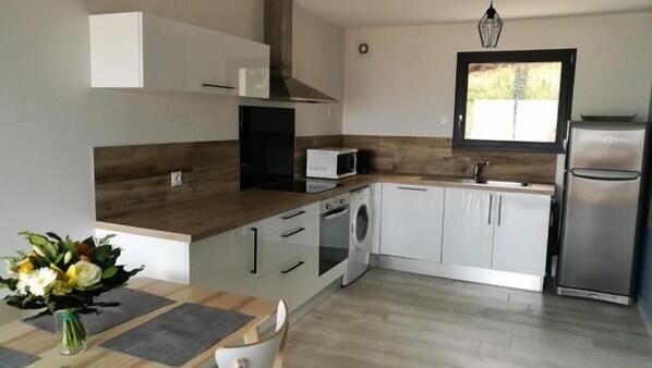 A modern kitchen with white cabinets, a stainless steel refrigerator, a microwave, and a built-in oven. - L'alphonsine (Veyre-Monton)
