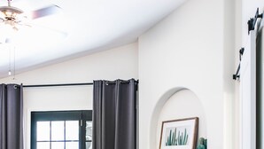 Ein modernes Schlafzimmer mit einem großen Bett, einem Kamin und einem Deckenventilator.