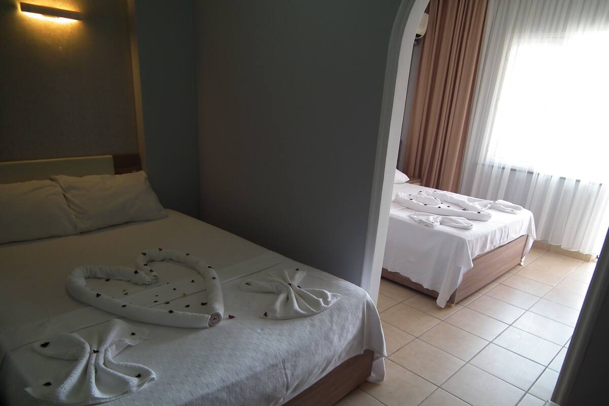 A hotel room with a large bed, a smaller bed, and a bathroom.