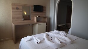 Una habitación de hotel con una cama, un escritorio, un televisor y un espejo.