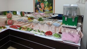 Una mesa de buffet con diversos alimentos y un dispensador de bebidas verde.