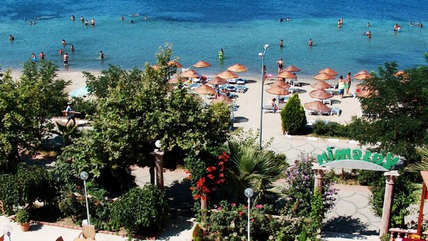 Un resort en la playa con aguas azul turquesa, sombrillas y un letrero que dice 'Ninety Degrees'.