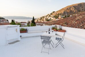 A rooftop terrace with a table, chairs, and potted plants.