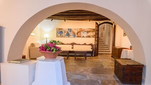 Una habitación acogedora con suelo de piedra, un sofá blanco, un banco de madera y una mesa con una planta en maceta.