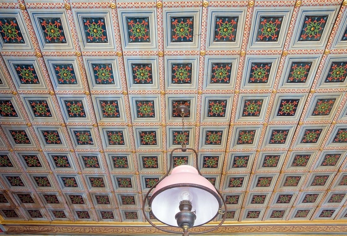 A ceiling with a grid of square panels, each with a floral pattern.
