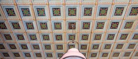 A ceiling with a grid of square panels, each with a floral pattern.