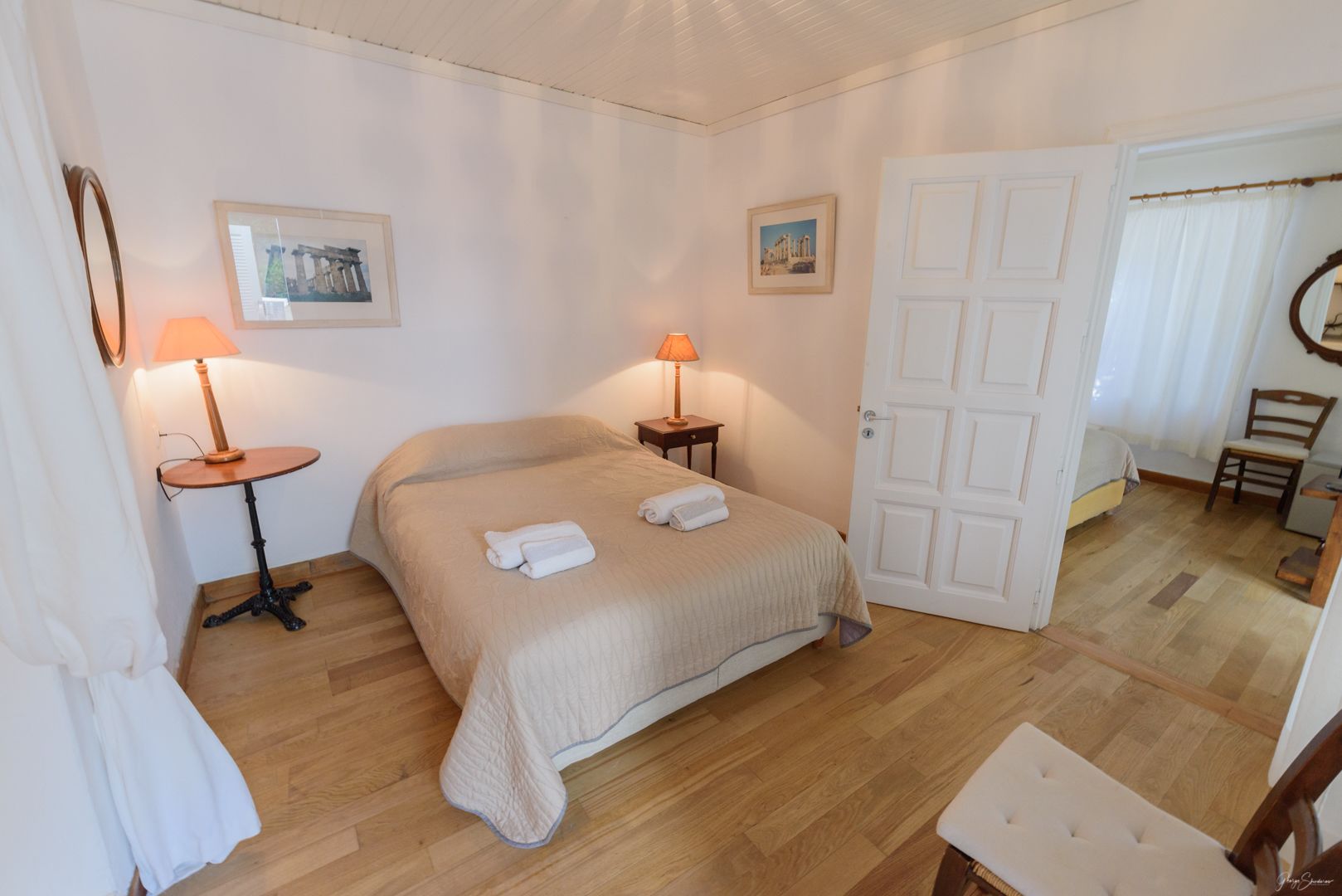 A bedroom with a bed, two bedside tables with lamps, a door, and a chair.