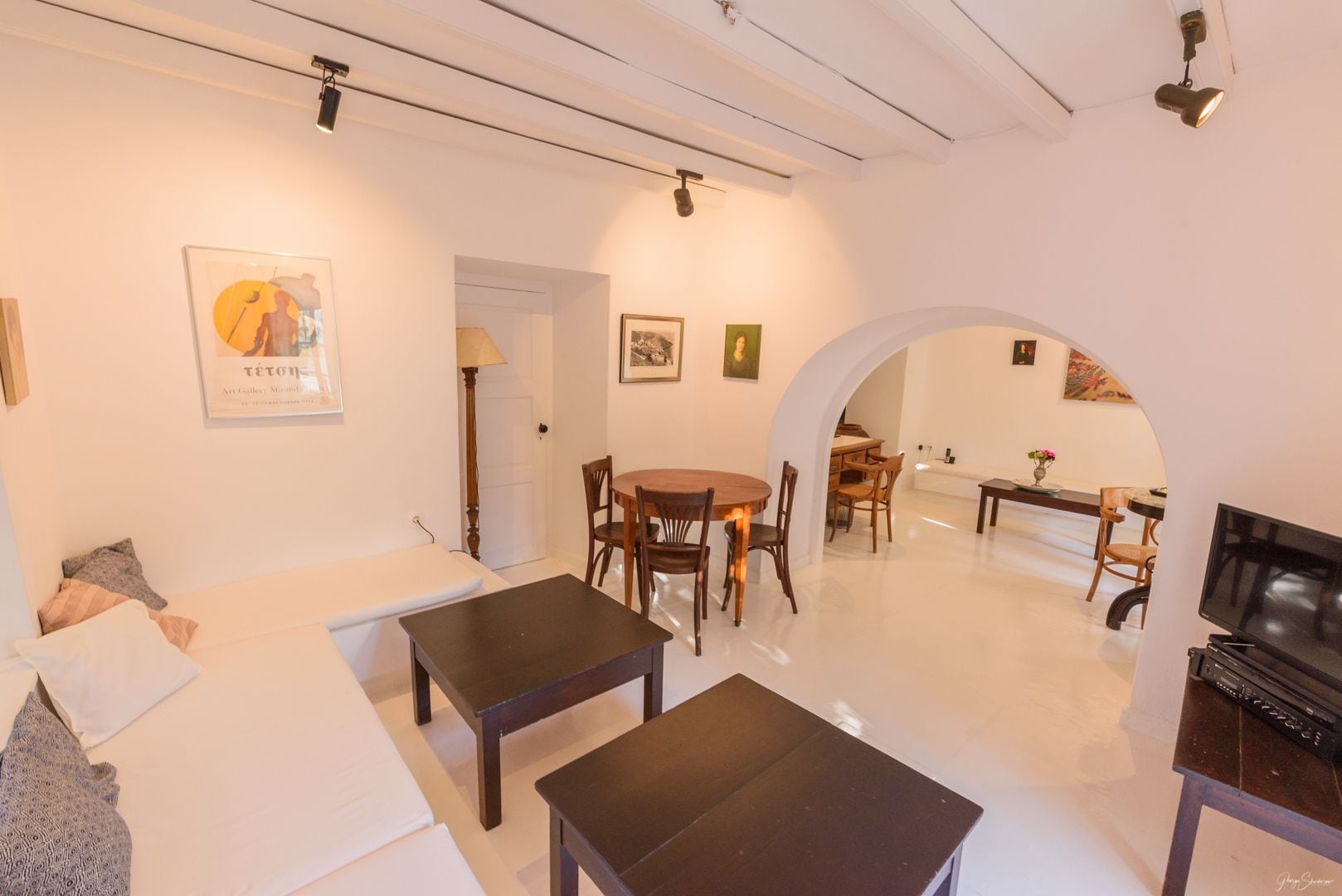 A living room with a sofa, two tables, a TV, and a dining area with chairs and a table.