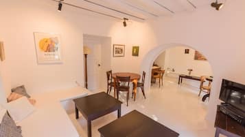 A living room with a sofa, two tables, a TV, and a dining area with chairs and a table.