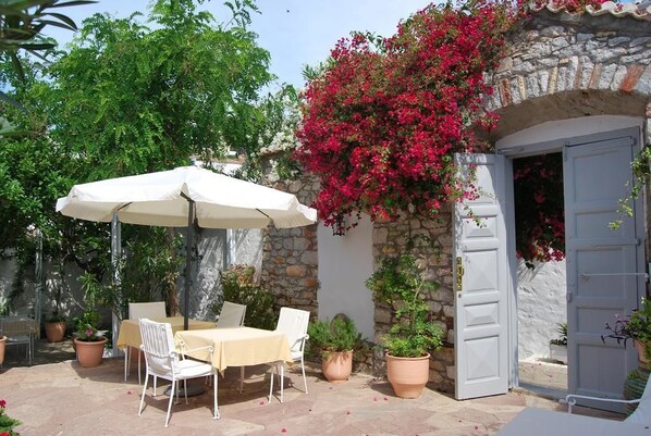 An outdoor patio with a table and chairs, surrounded by potted plants and a stone wall.